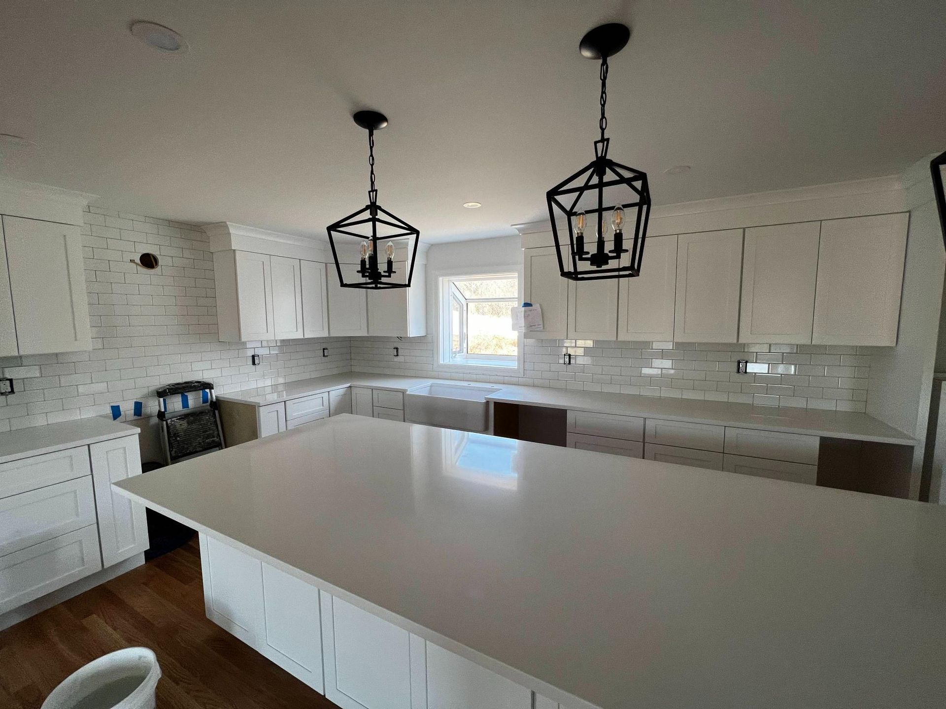 Bright white kitchen with a large island, pendant lights, and white cabinets