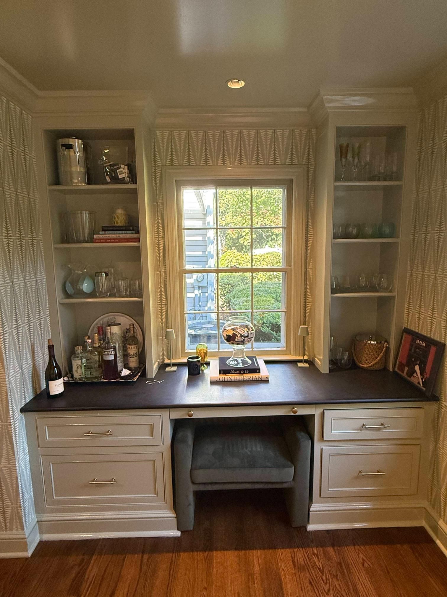 Built-in home office nook with desk, shelves, and window overlooking greenery