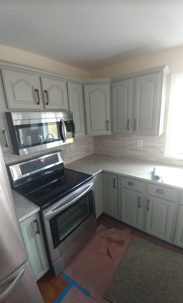 Kitchen corner with gray cabinets, black stove, and white countertop.