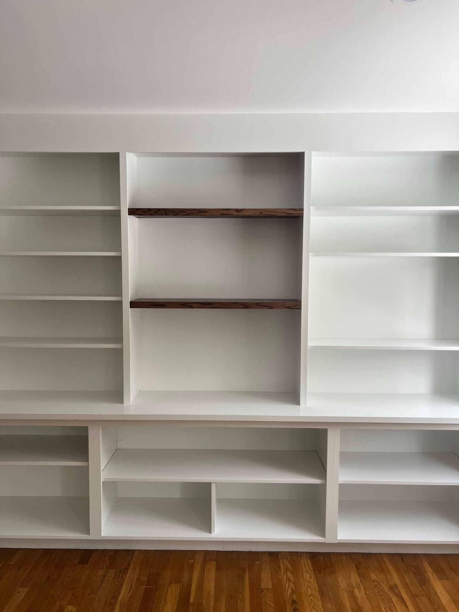 White built-in shelving unit with multiple empty shelves and cubbies against a white wall.