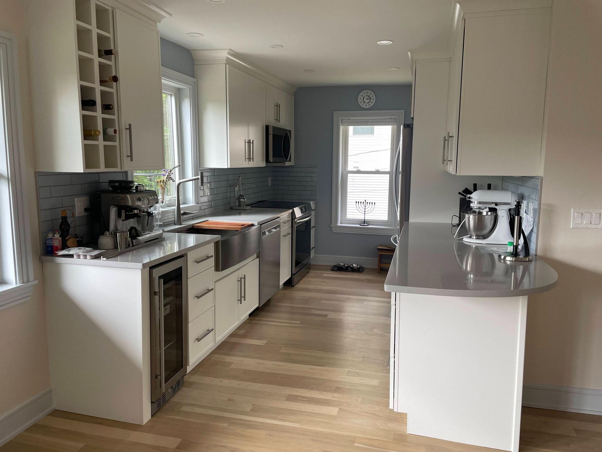 Bright modern kitchen with white cabinets, stainless appliances, and wood floors