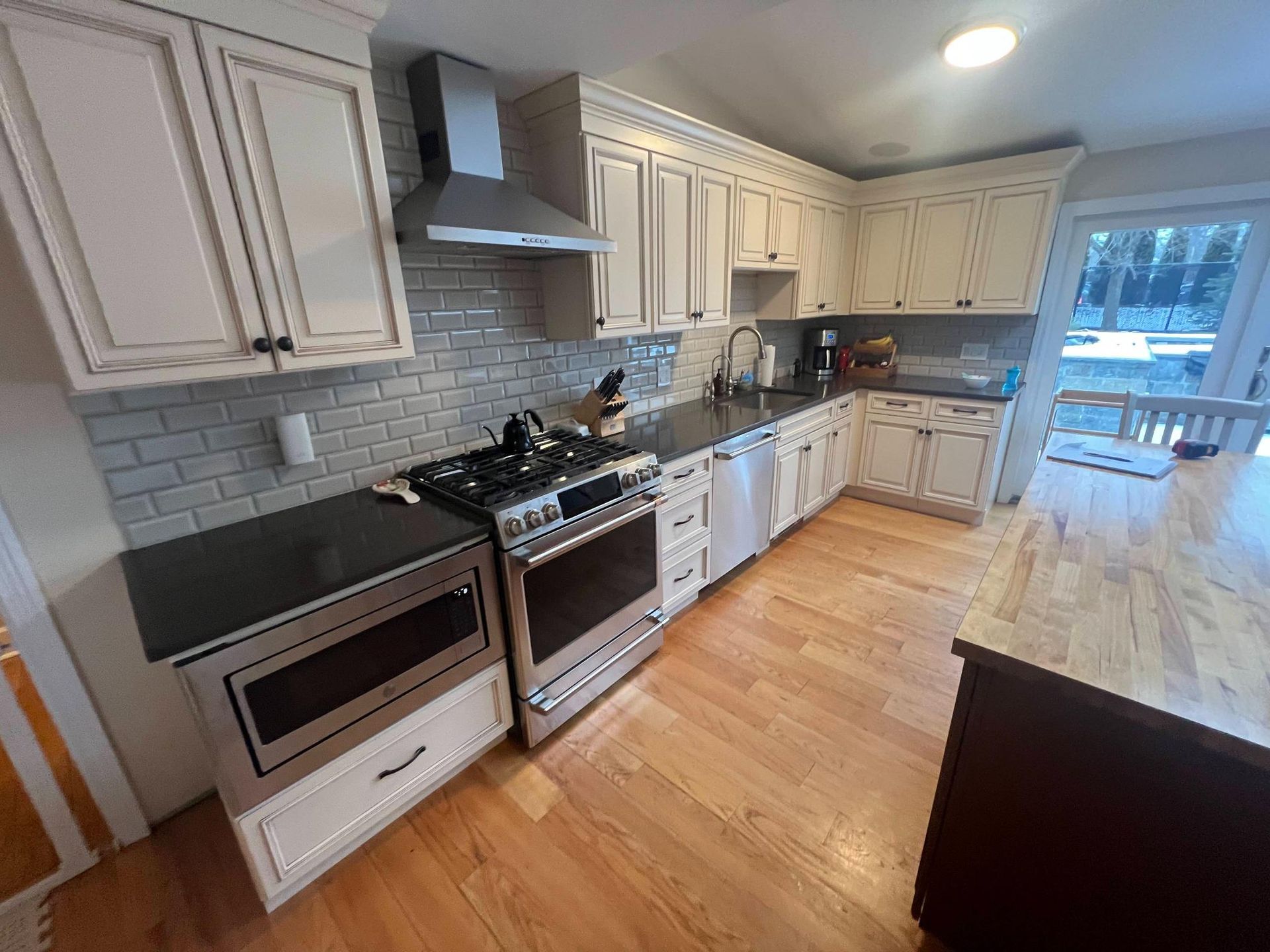 Bright modern kitchen with white cabinets, stainless steel appliances, and light wood floors