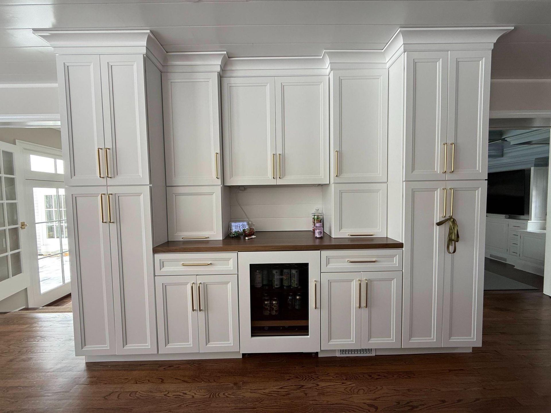 White built-in cabinetry with brass handles, wood countertop, and a small oven in a bright kitchen alcove