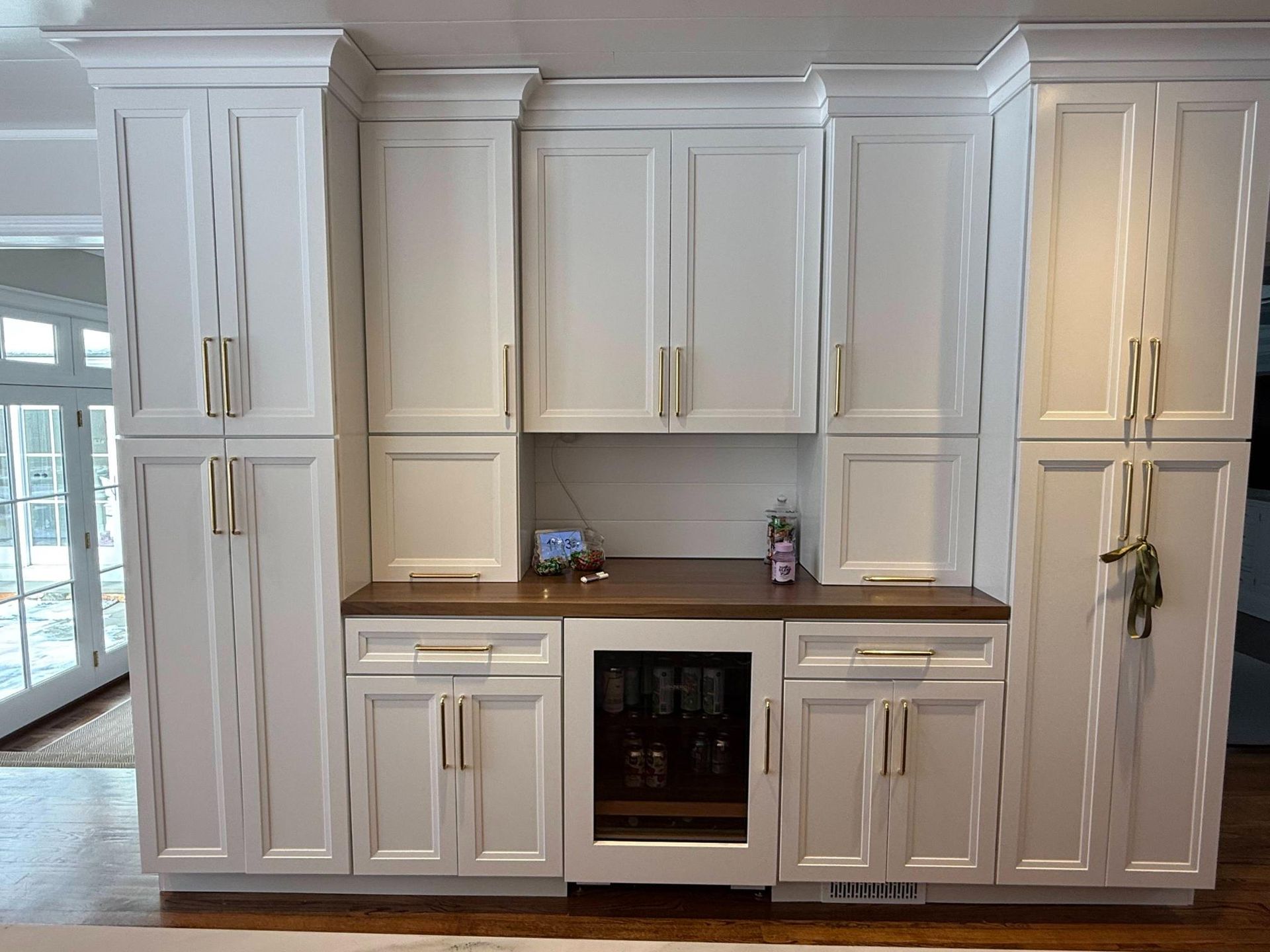 White built-in kitchen cabinets with wood countertop and stainless oven in a bright room