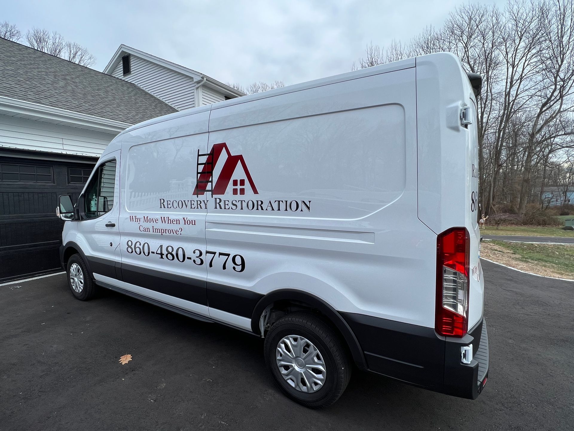 White van with “Restoration” branding parked in a driveway beside a house.
