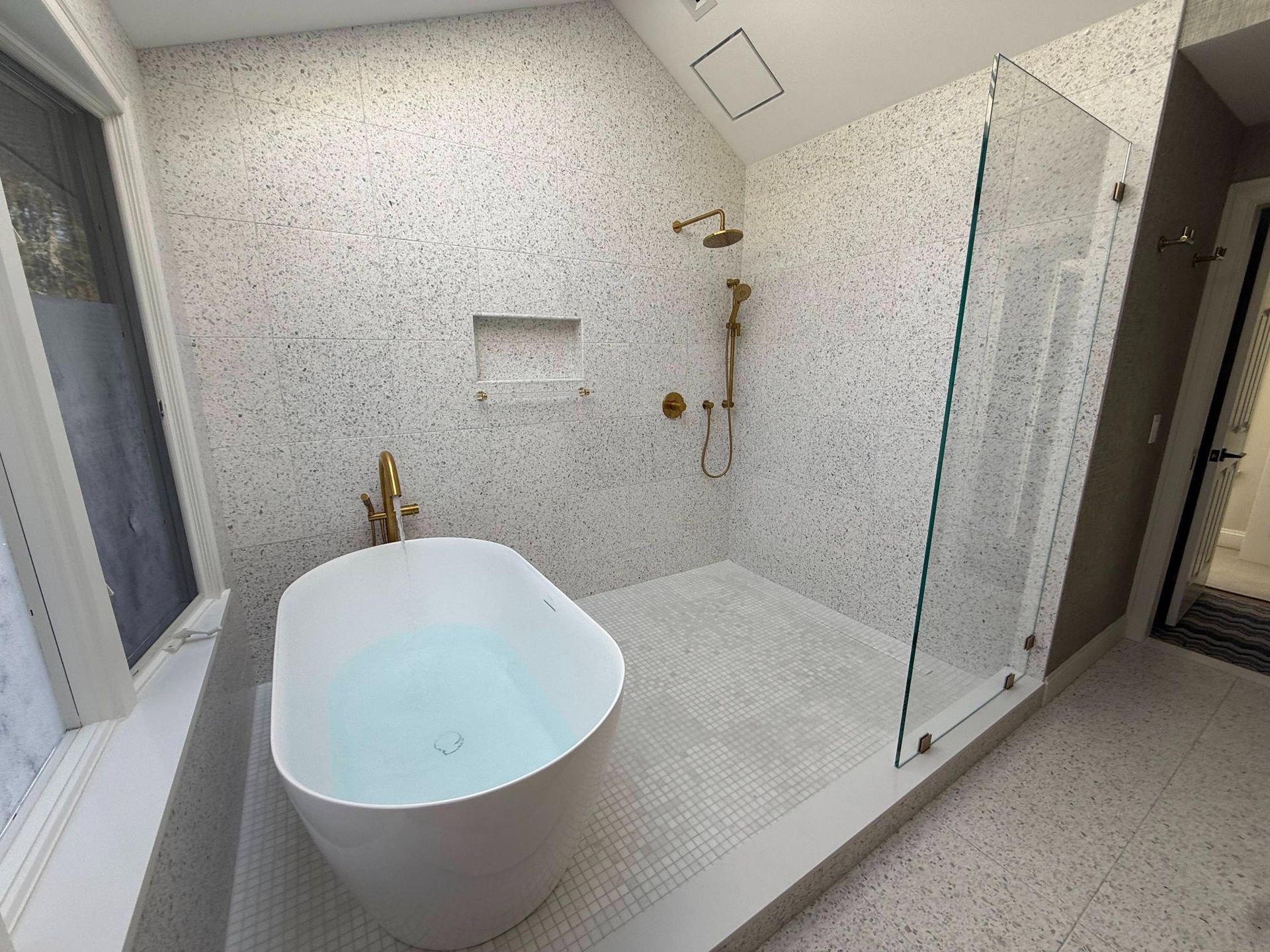Modern bathroom with a freestanding tub, gold fixtures, and a glass shower enclosure