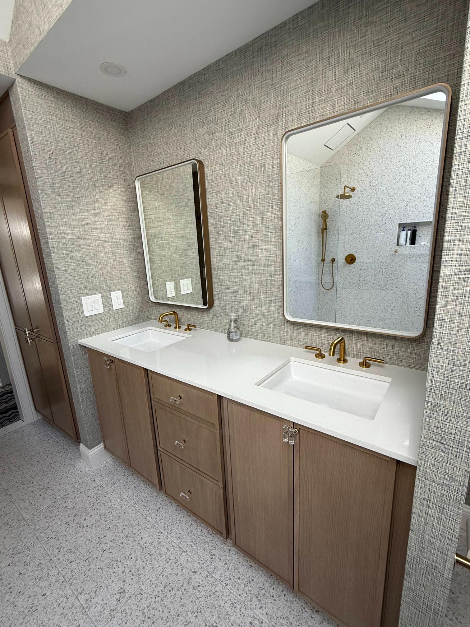 Modern bathroom vanity with double sinks, mirrors, and beige textured walls