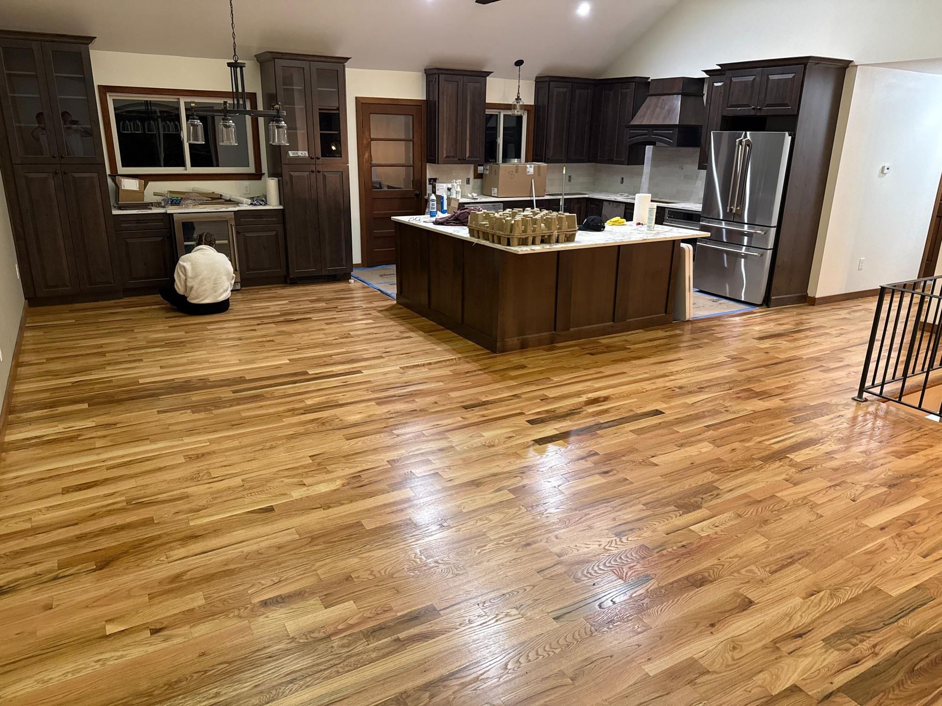 Spacious kitchen with dark wood cabinets, stainless steel appliances, island, and glossy hardwood floors