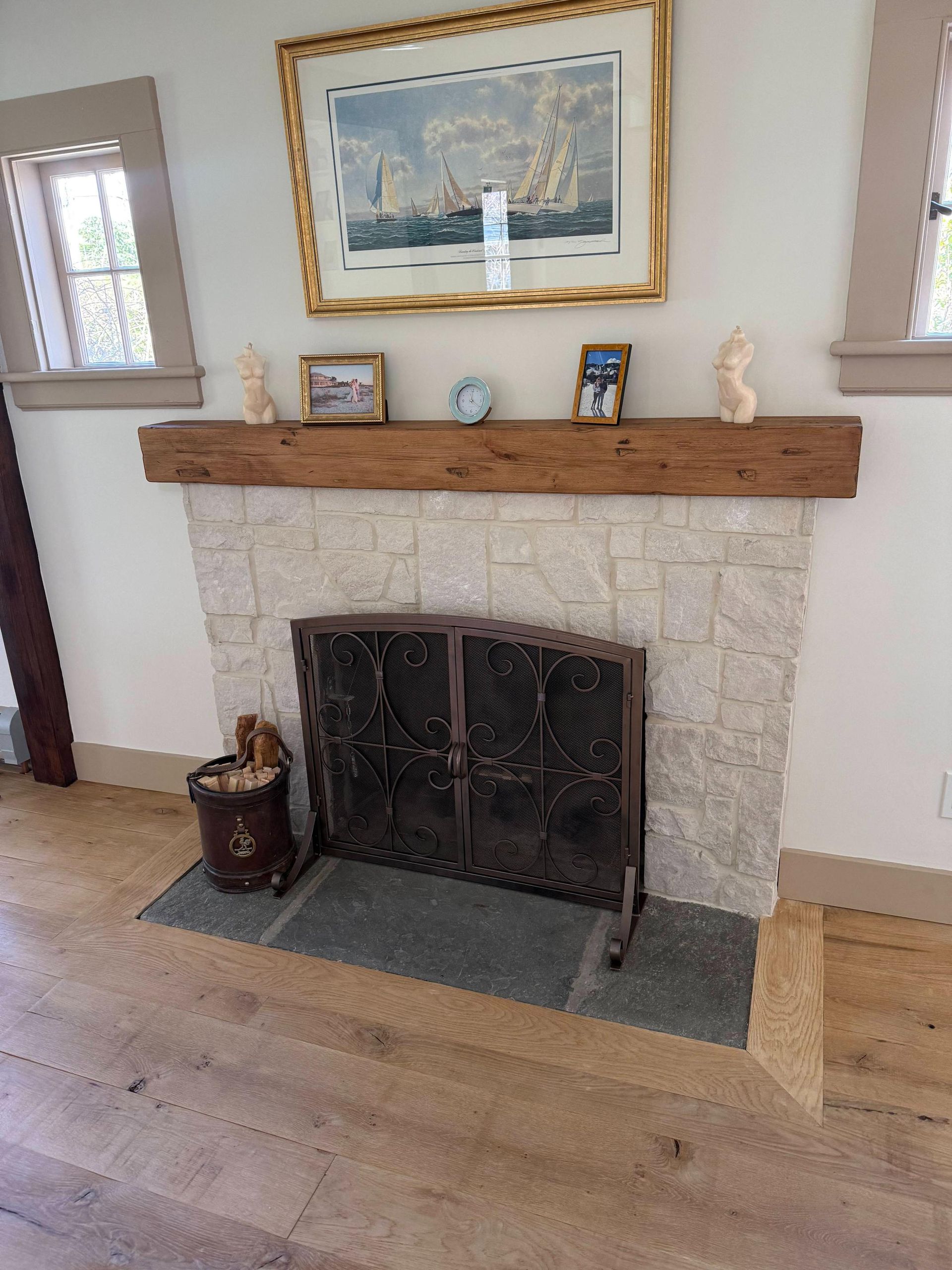 Stone fireplace with wooden mantel, framed art, and small decor in a bright living room