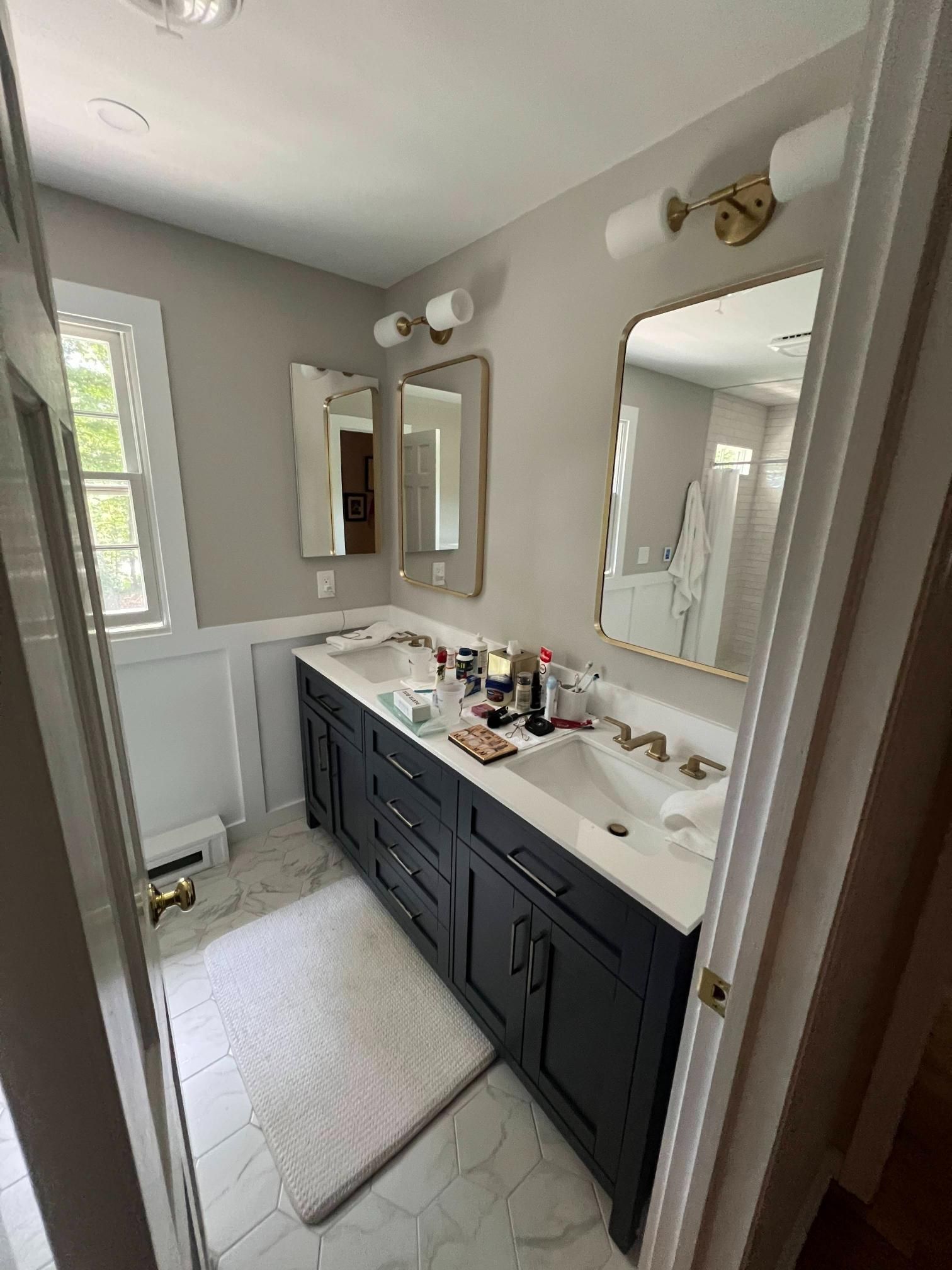 Bathroom with dark vanity, double sinks, large mirror, and light tile floor.