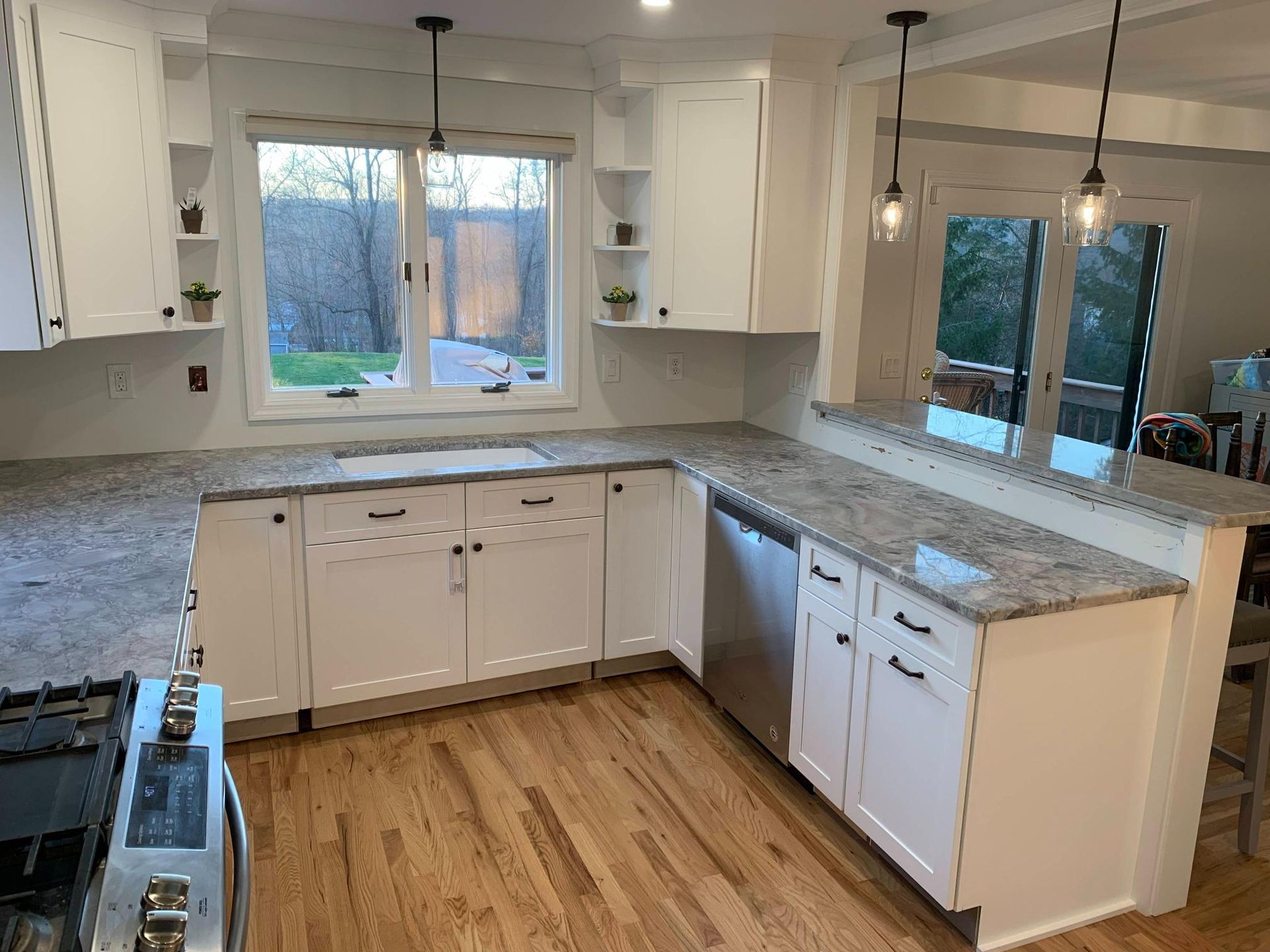 Bright kitchen with white cabinets, gray countertops, and a large window above the sink