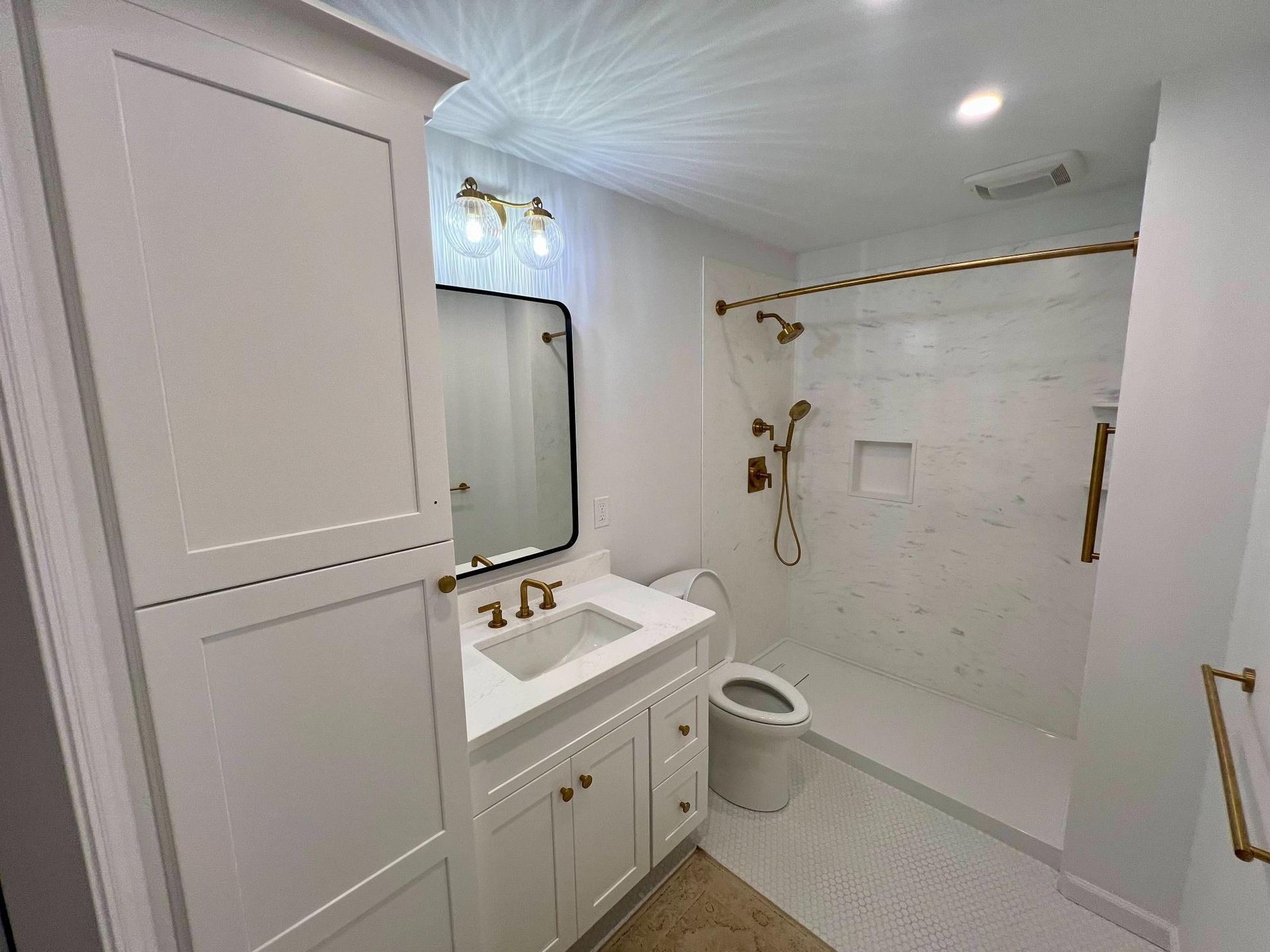 Bright white bathroom with vanity, mirror, toilet, and tiled shower area.