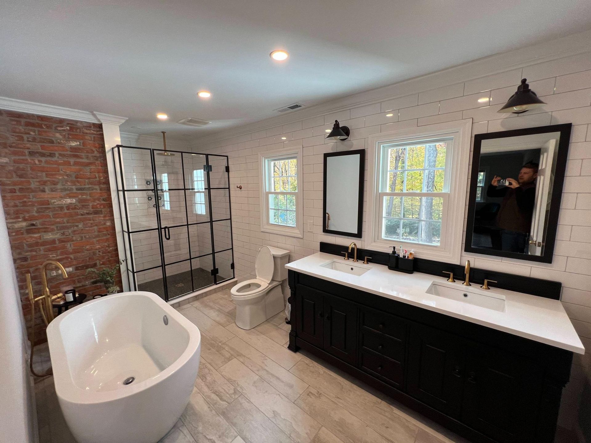 Modern bathroom with freestanding tub, black vanity, white shiplap walls, and glass shower.