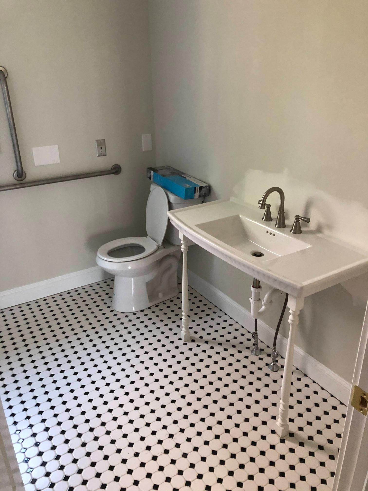 Small bathroom with a toilet, white sink, and black-and-white tile floor.