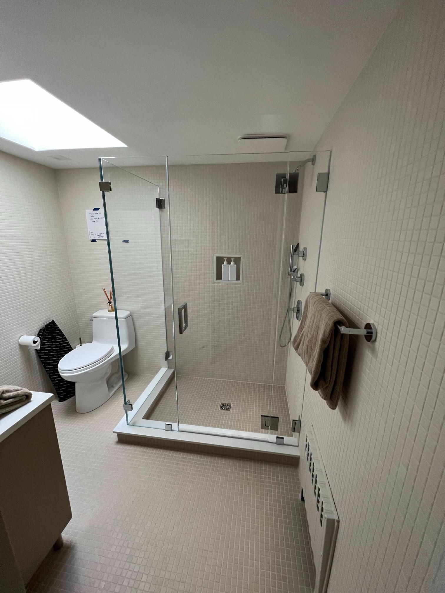 Accessible bathroom with walk-in shower, toilet, and sink in a beige tiled room