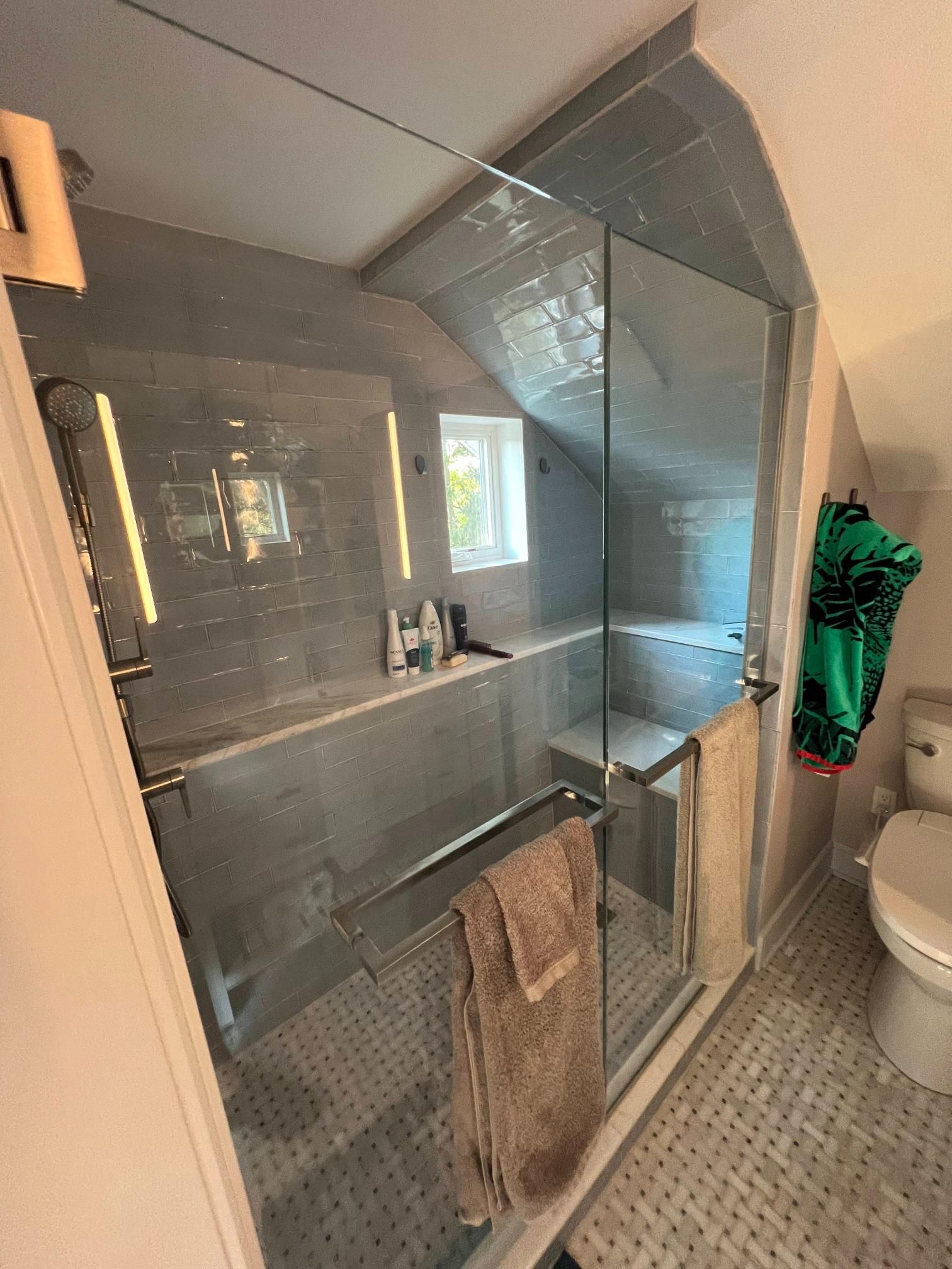 Modern bathroom with glass shower, gray tile floor, vanity sink, mirror, and white toilet