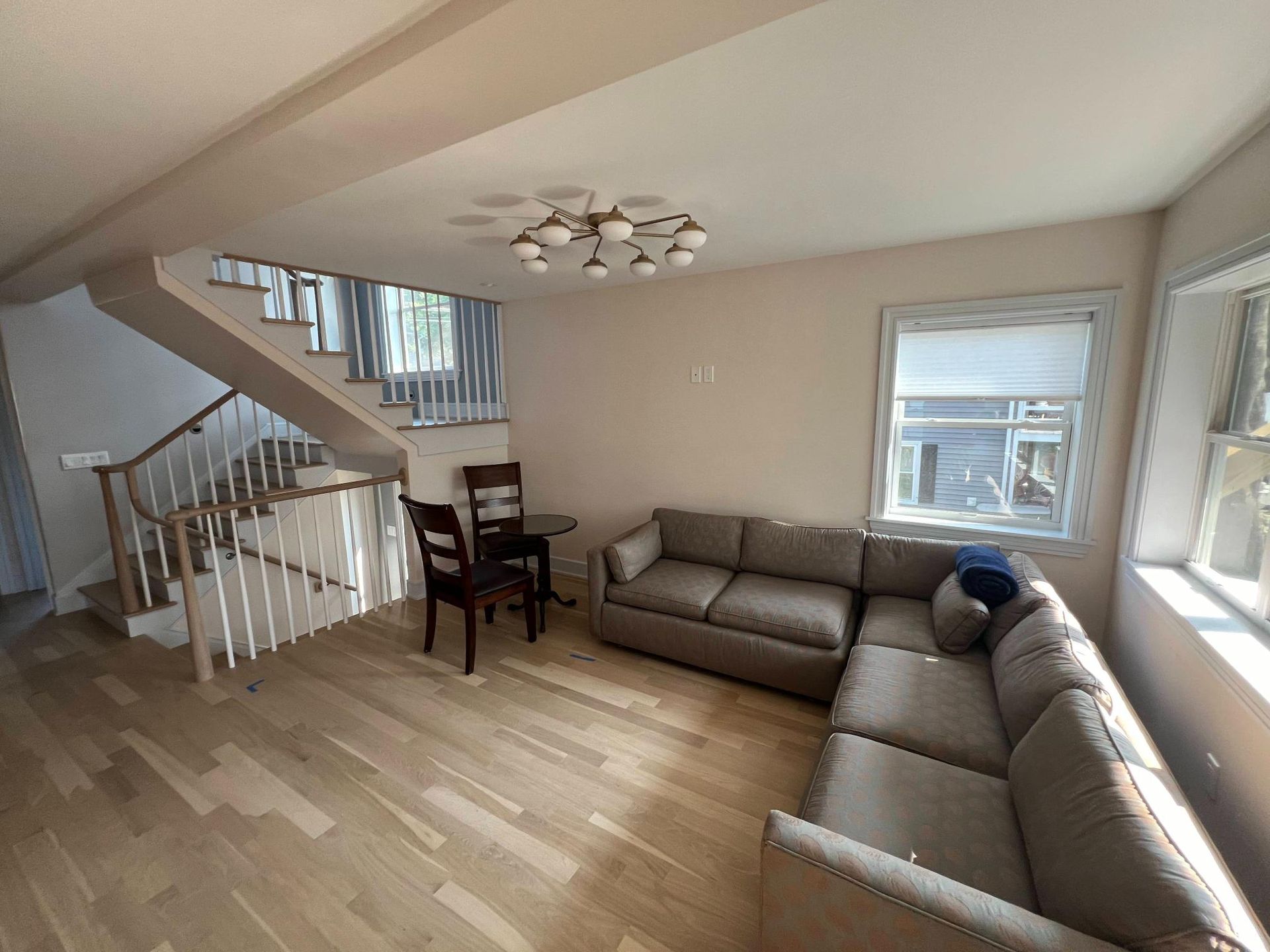 Bright living room with beige sectional sofa, staircase, and large window with mountain view
