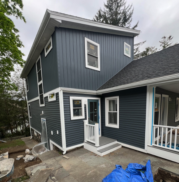 Blue-gray two-story house exterior with white trim and small front porch, viewed from the side