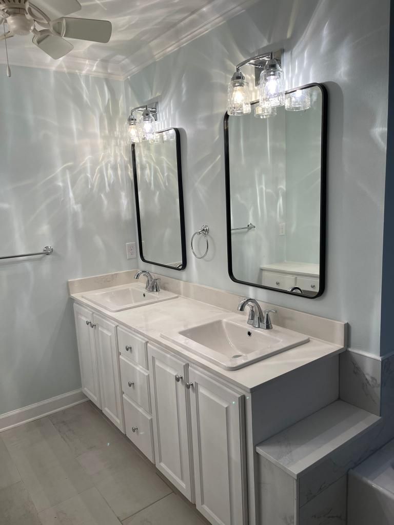 Double vanity bathroom with white cabinets, black-framed mirrors, and wall sconces