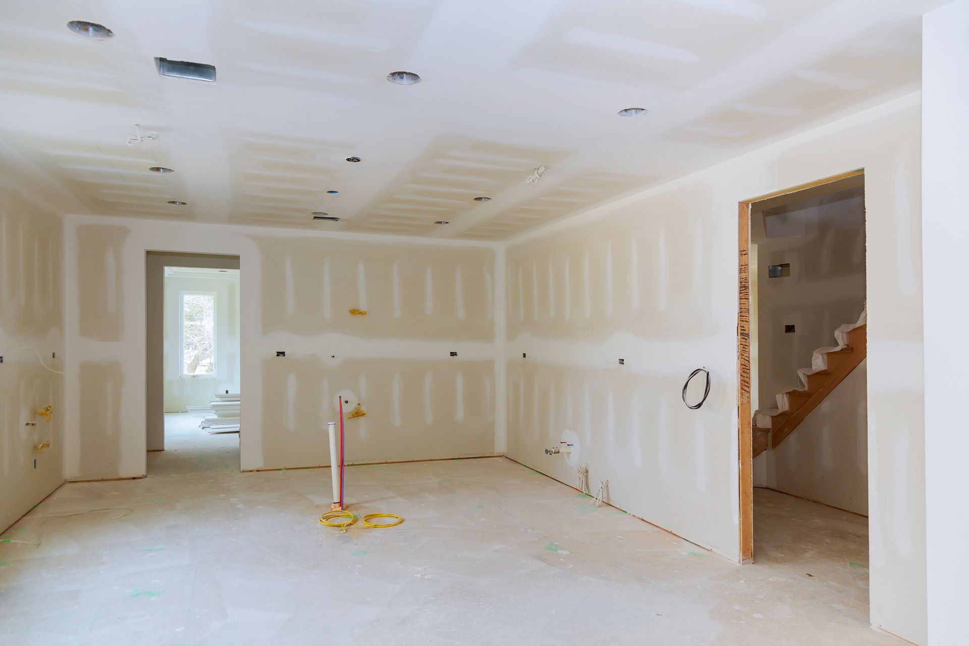 An empty room in a house under construction with drywall on the walls.