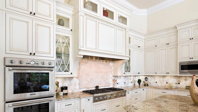 A kitchen with white cabinets , granite counter tops , and stainless steel appliances.