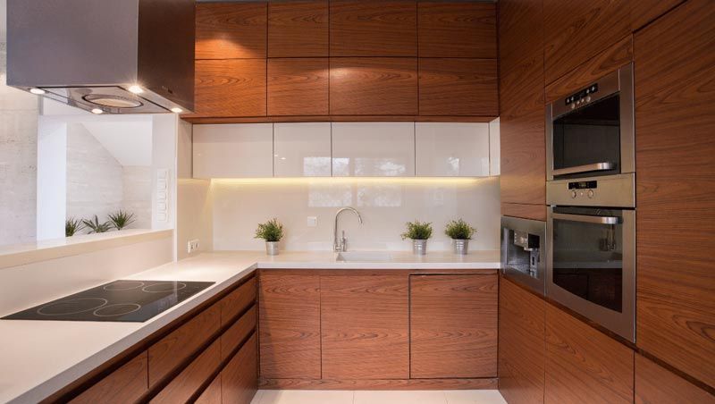 A kitchen with wooden cabinets , stainless steel appliances , and a stove top oven.