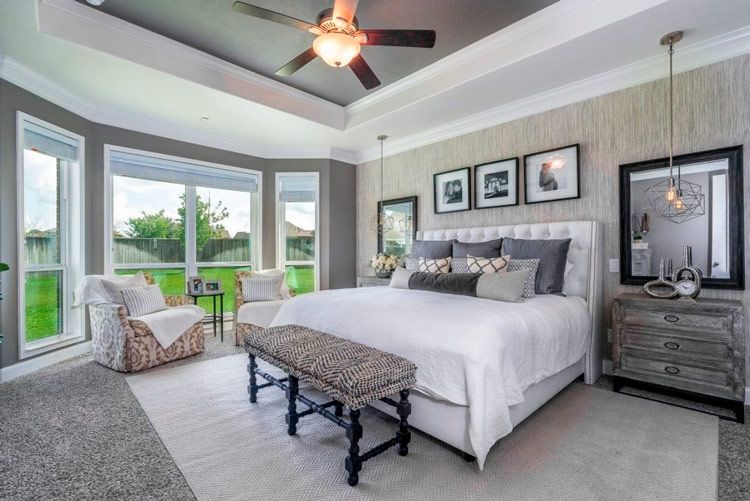 A bedroom with a king size bed , a bench , a dresser , and a ceiling fan.