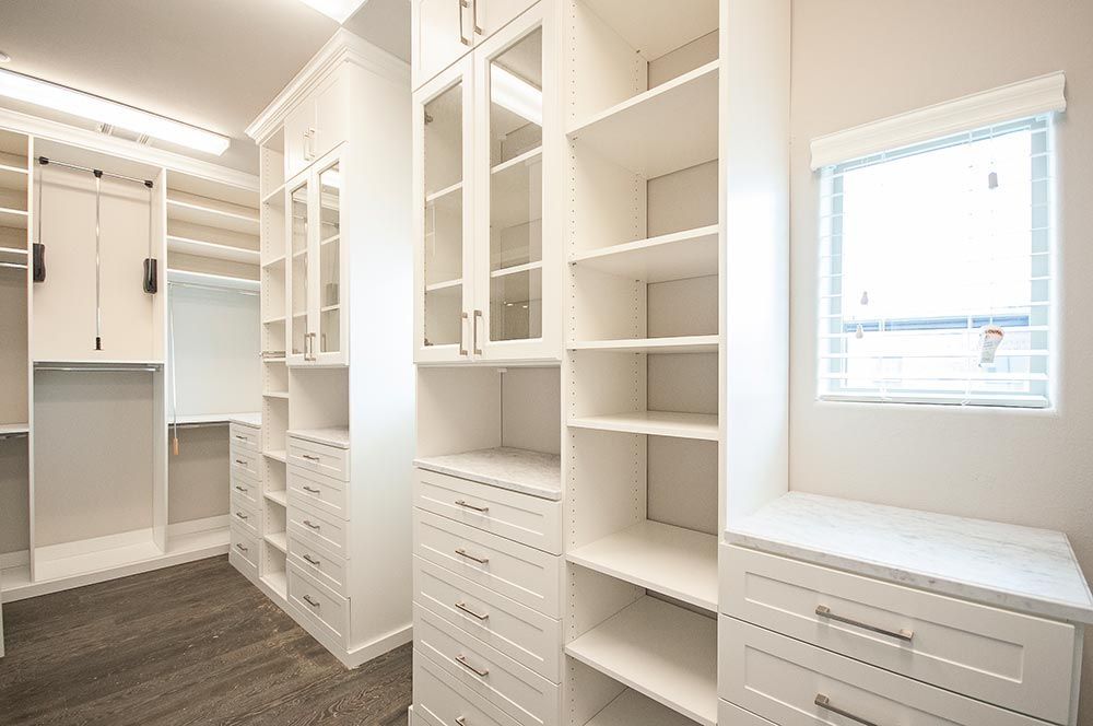 A walk in closet with lots of shelves and drawers and a window.