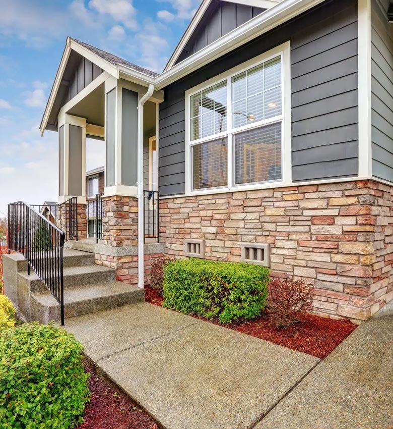 The front of a house with a stone wall and stairs leading up to it.