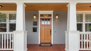 The front door of a house with a porch and a wooden door.