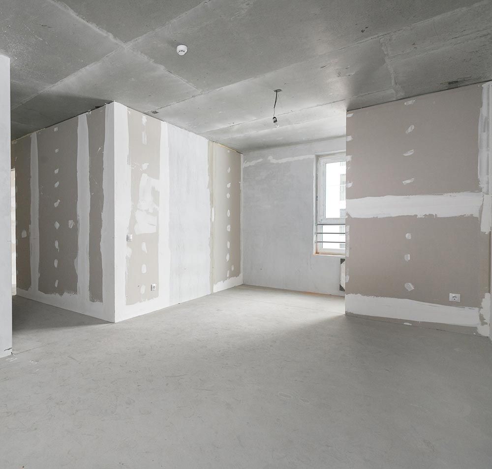 An empty room with drywall on the walls and a window.