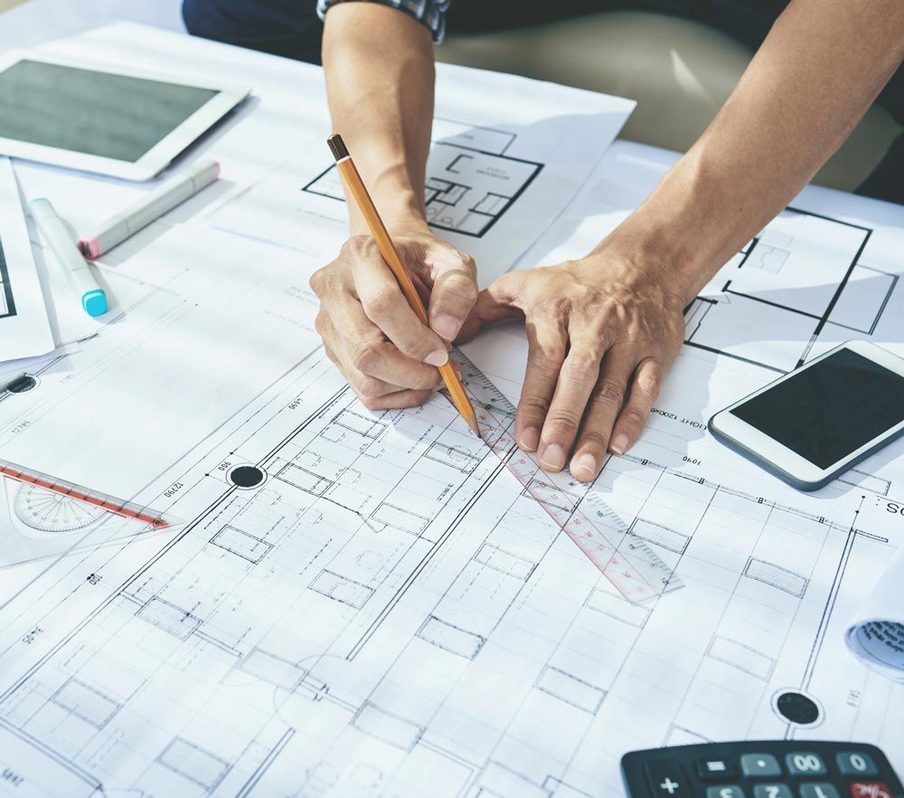 A person is measuring a blueprint with a ruler and pencil