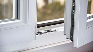 A close up of a white window with the window open.