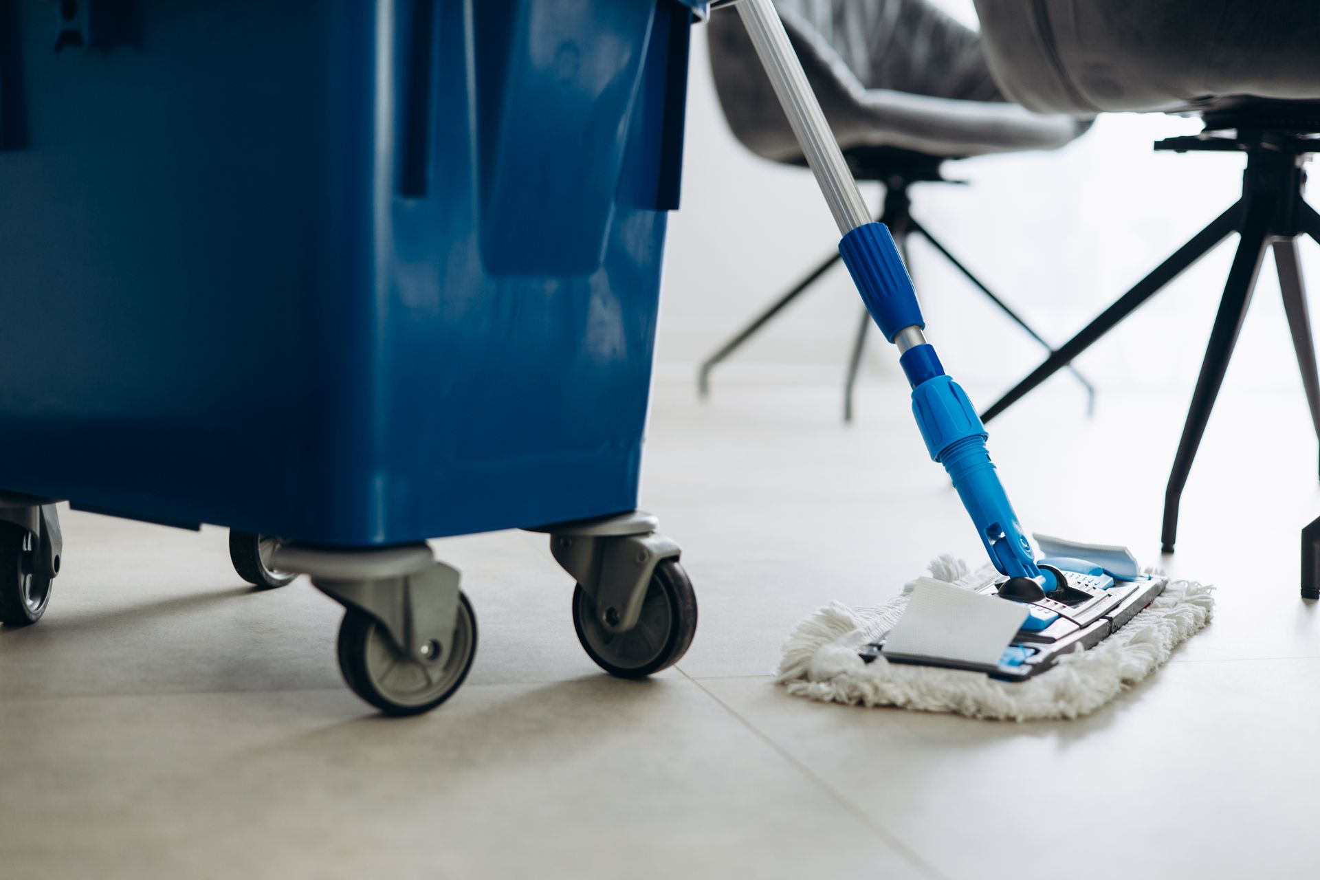 Blue cleaning cart and mop head on a tiled floor