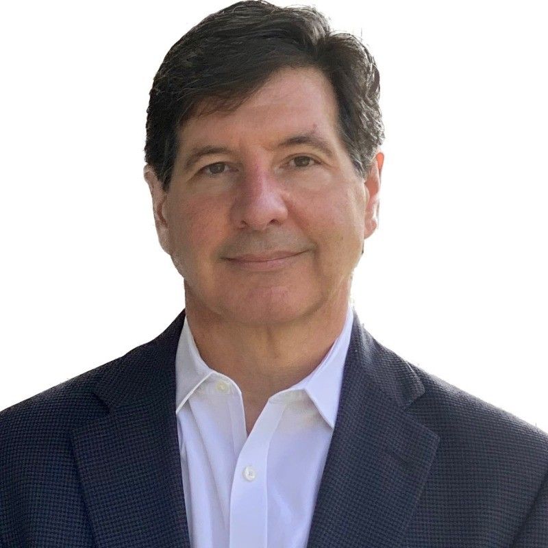 Man in a navy blazer and white shirt, smiling, head and shoulders shot.