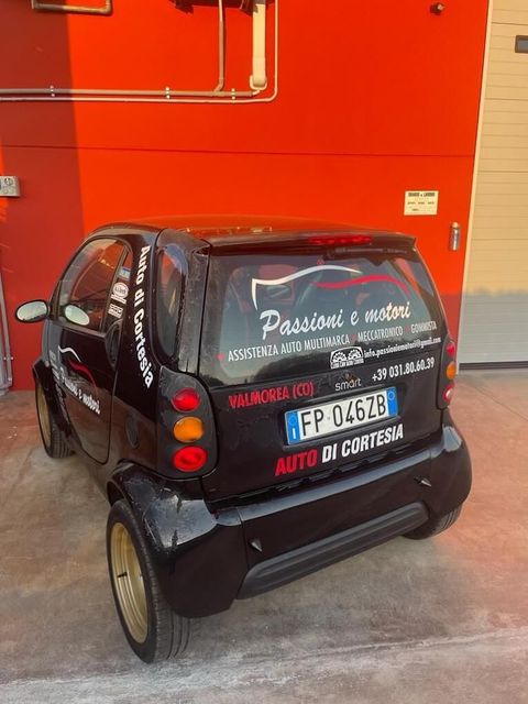 Un'auto nera è parcheggiata davanti a un edificio rosso.