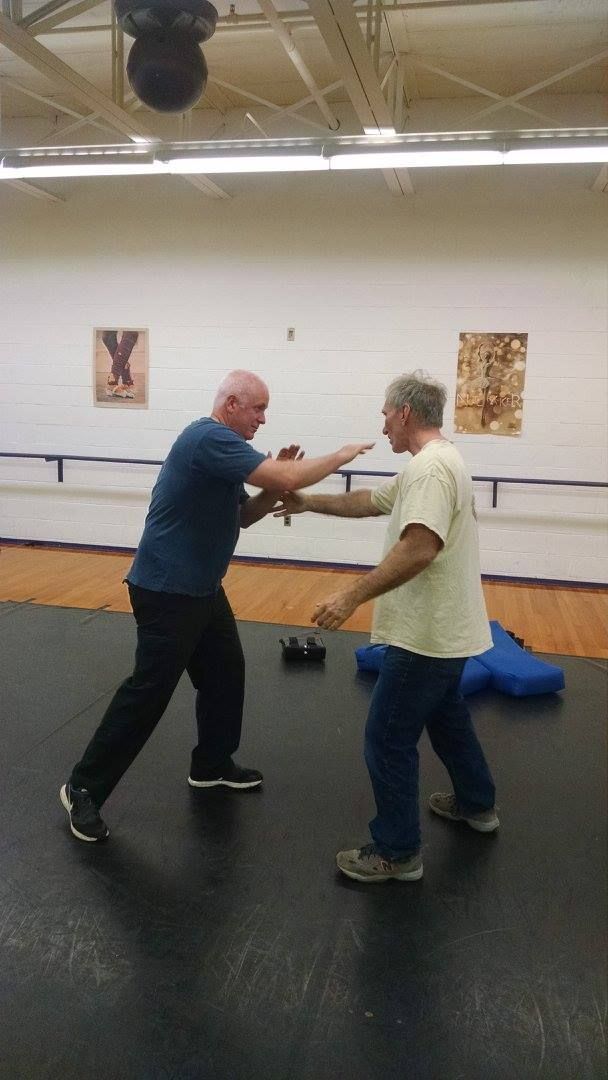 Two men practicing martial arts in a gym. One throws a punch while the other blocks.