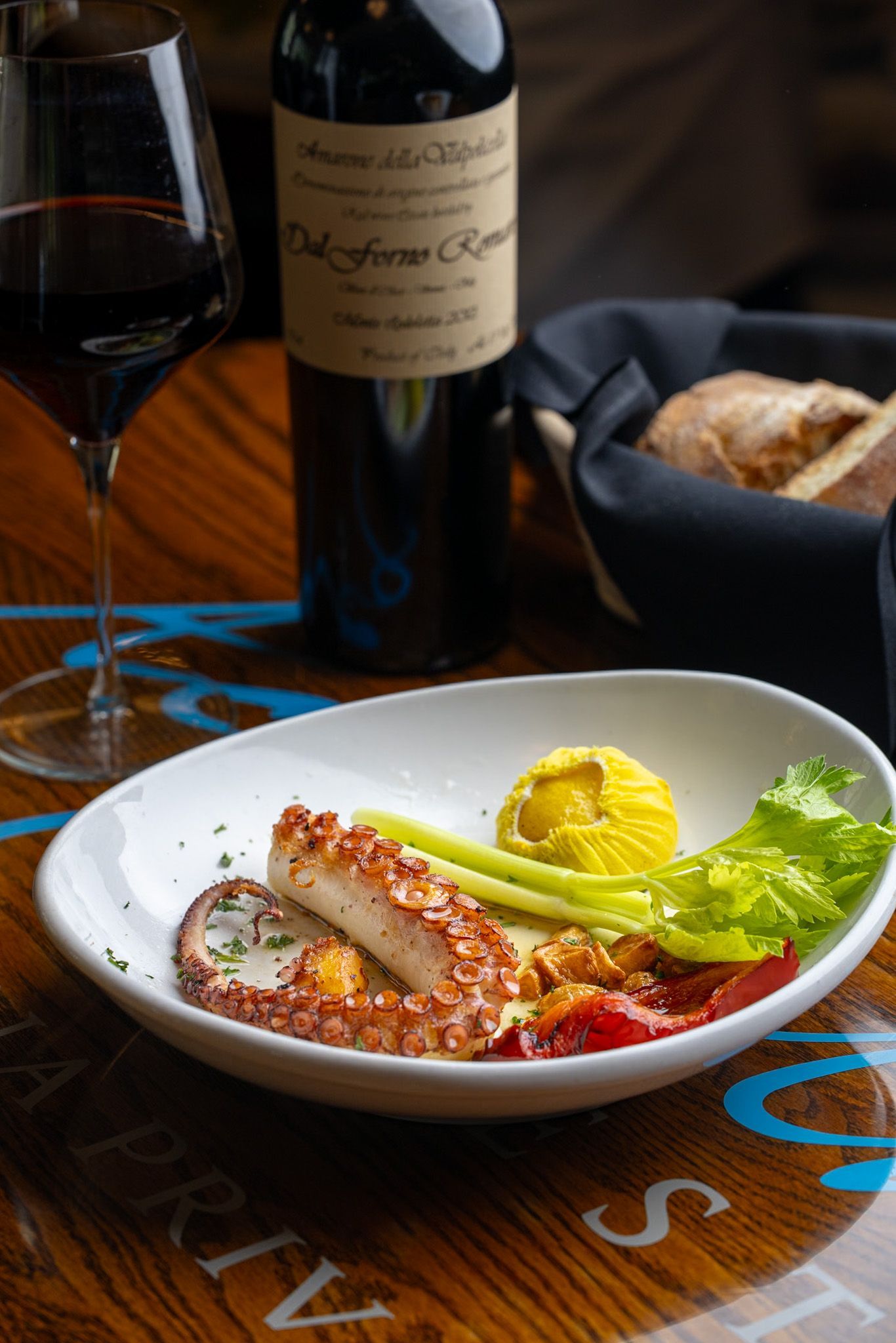 A plate of food and a bottle of wine on a table.