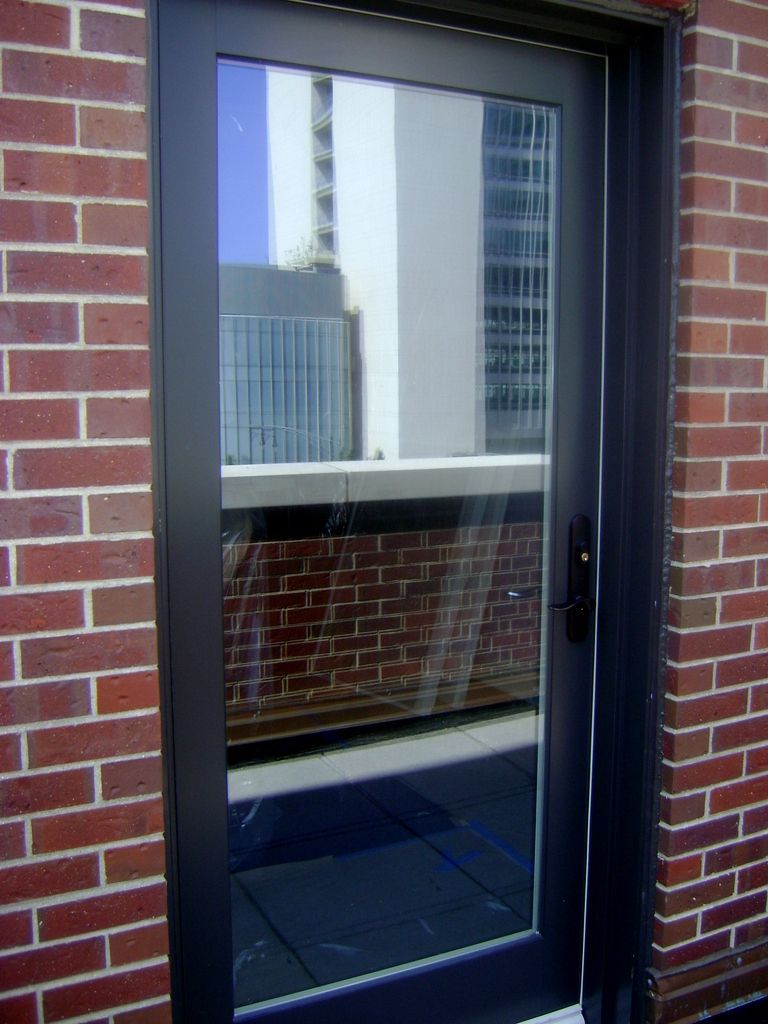 A black door with a brick wall behind it