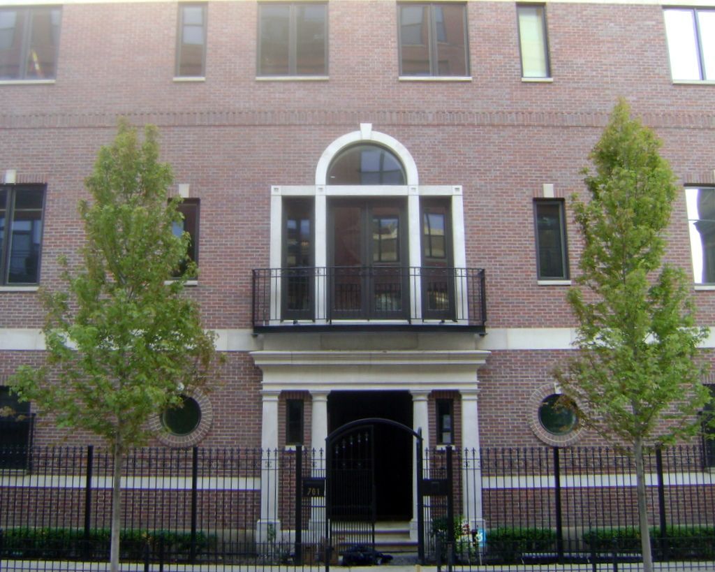 A brick building with a balcony and trees in front of it