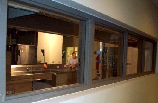 A man is standing in a kitchen looking out a window