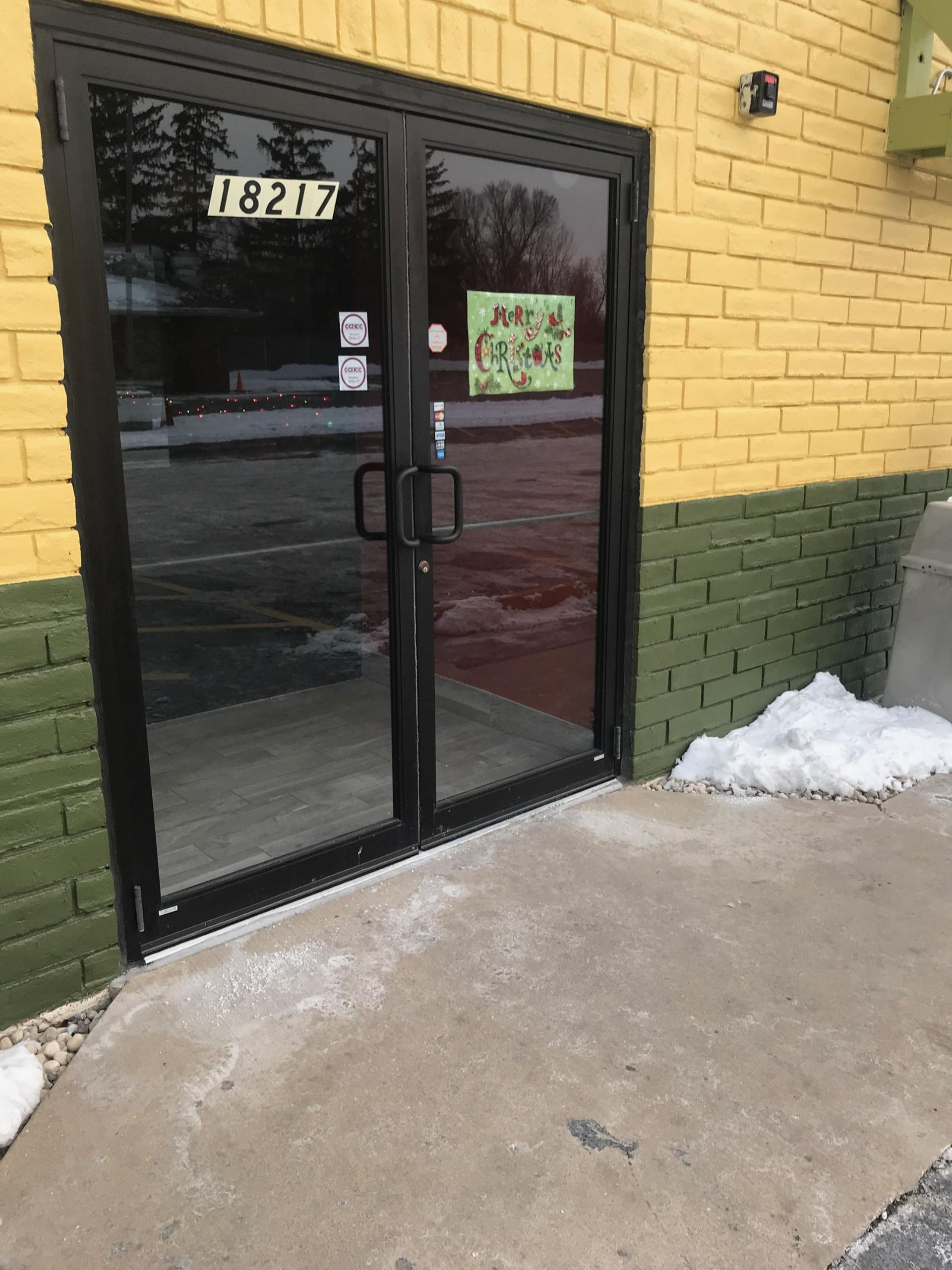 A yellow and green brick building with a black door