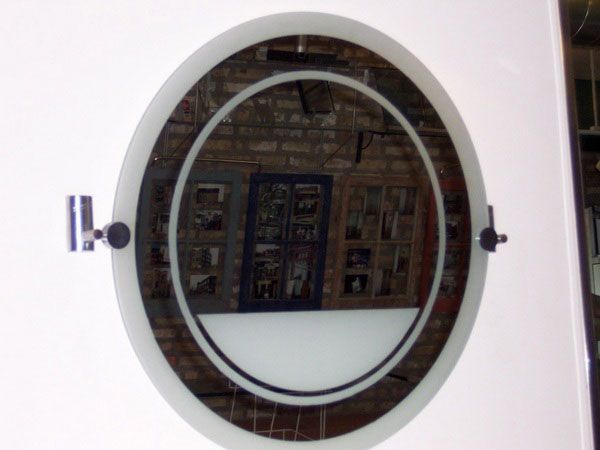 A round mirror on a white wall with a brick wall in the background.