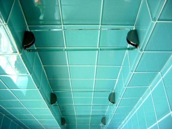 A bathroom with blue tiles and a glass shelf