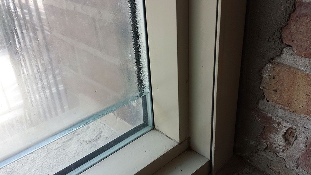 A close up of a window with a brick wall in the background.