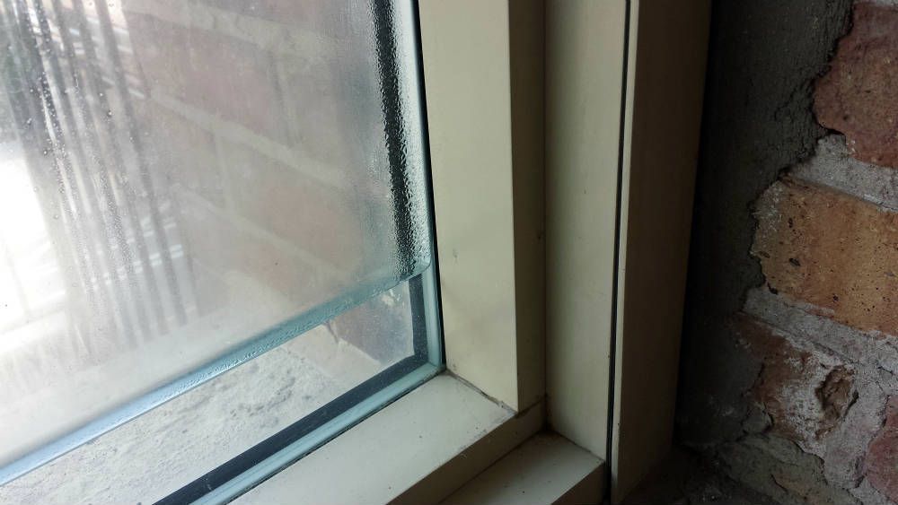 A close up of a window with a brick wall in the background.