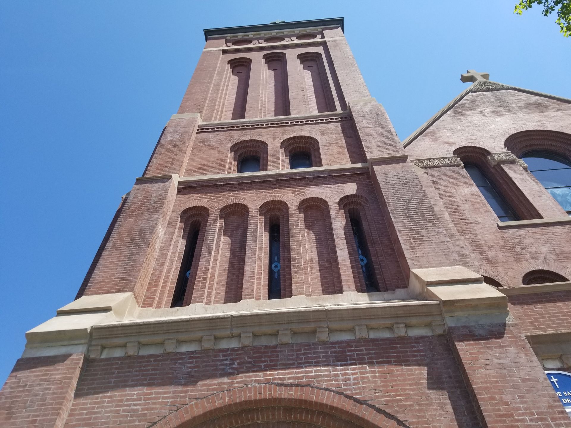 Looking up at a tall brick building with a blue sign in front of it