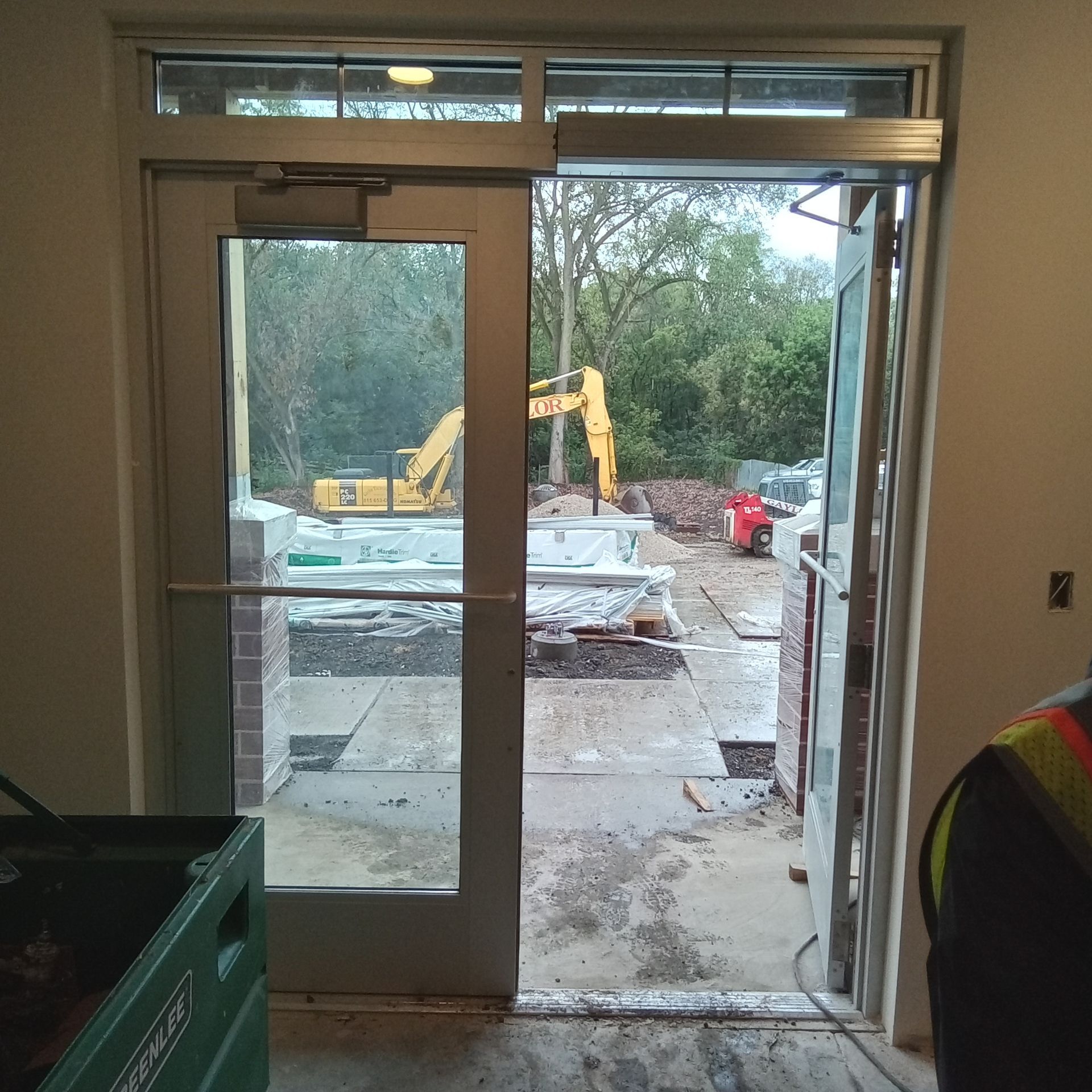A construction site is visible through a glass door
