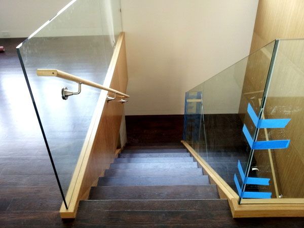 A staircase with a glass railing and blue tape on the steps