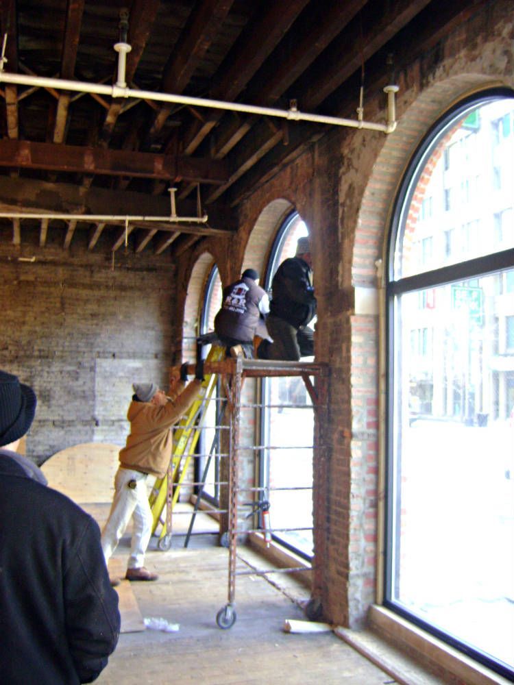 A man on a ladder in a room with arched windows